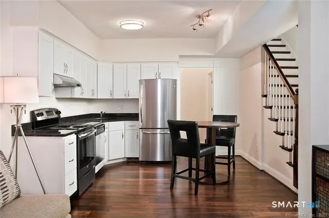 a kitchen with granite countertop a stove top oven a sink dishwasher and a dining table with wooden floor