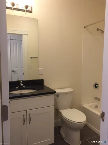 a bathroom with a granite countertop toilet a sink and a mirror