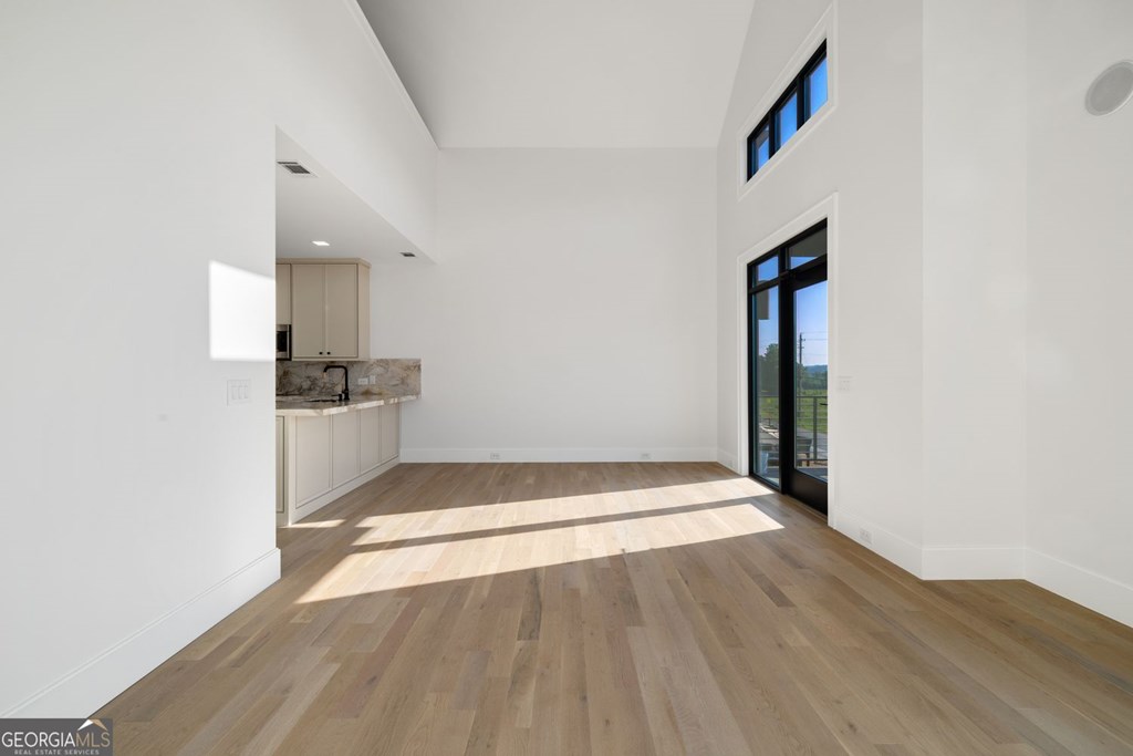 1281 East Main Street Blue Ridge, GA 30513 - Photo 3 of 19 an empty room with wooden floor and kitchen