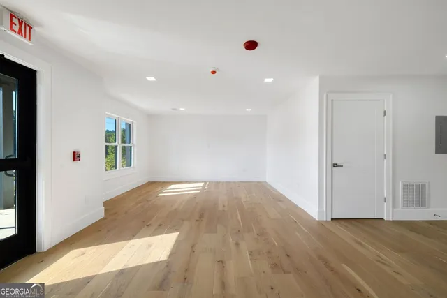 an empty room with wooden floor and windows