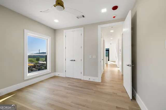 a view of an empty room with wooden floor and a window