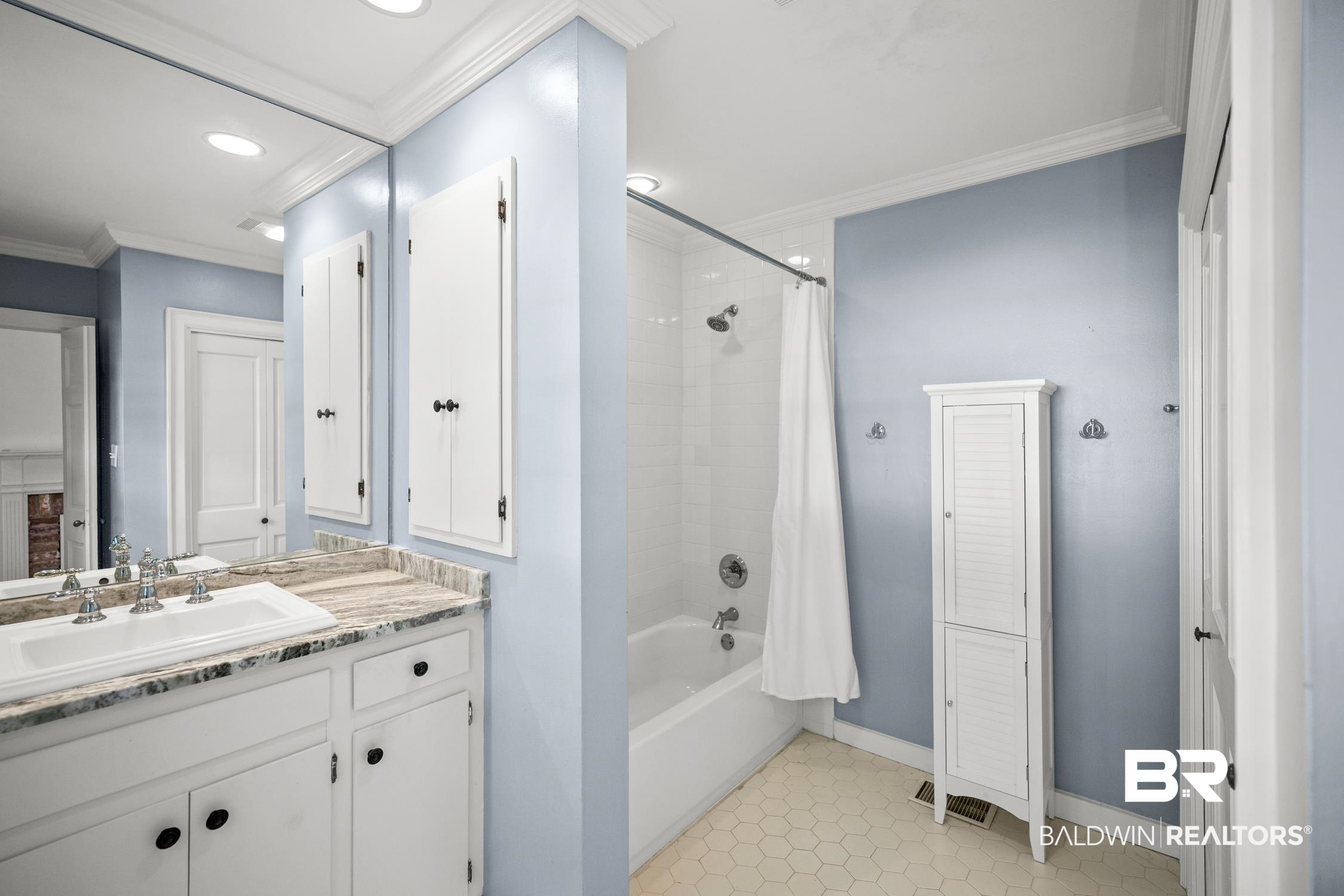5490 Battles Road Fairhope, AL 36532 - Photo 24 of 47 Bathroom featuring a white vanity with a rectangular sink and stone-look countertop, built-in medicine cabinets, white subway tile shower surround, and hexagonal tile flooring