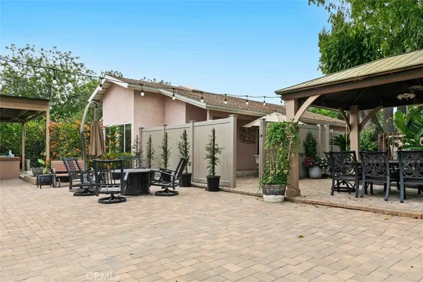 a view of the patio with chairs and tables under an umbrella
