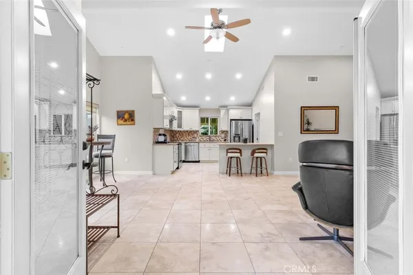 a kitchen with stainless steel appliances kitchen island granite countertop a refrigerator oven a sink a dining table and chairs with wooden floor
