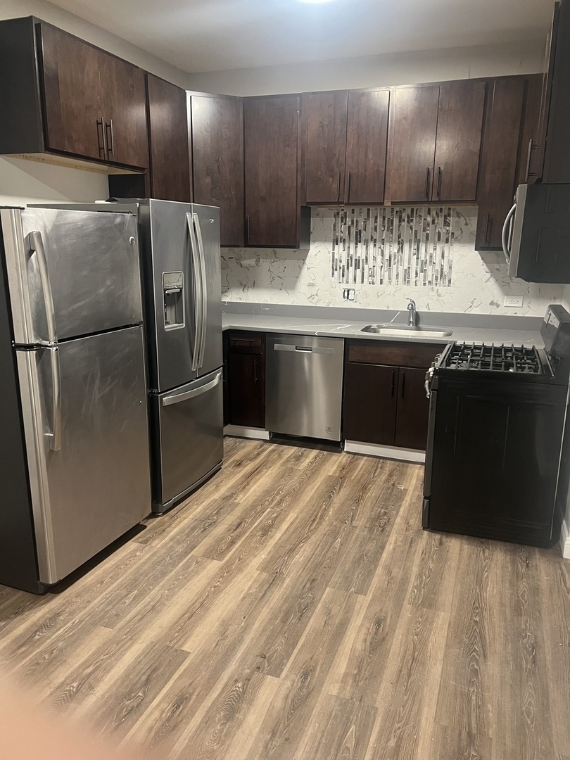 1434 South St Louis Avenue, Unit 1 Chicago, IL 60623 - Photo 2 of 9 a kitchen with kitchen island granite countertop a refrigerator stove and oven