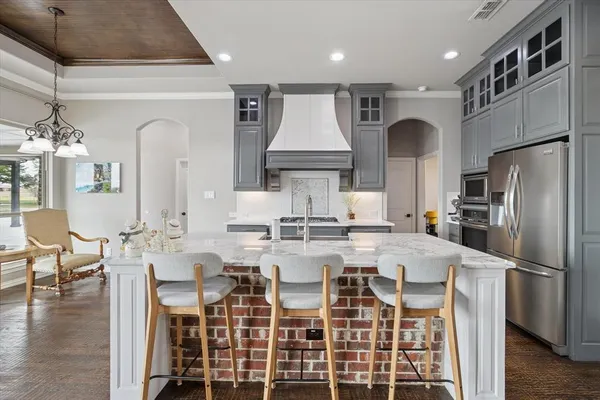 a kitchen with stainless steel appliances kitchen island granite countertop a table chairs stove and refrigerator