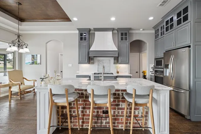 a kitchen with stainless steel appliances kitchen island granite countertop a table chairs stove and refrigerator