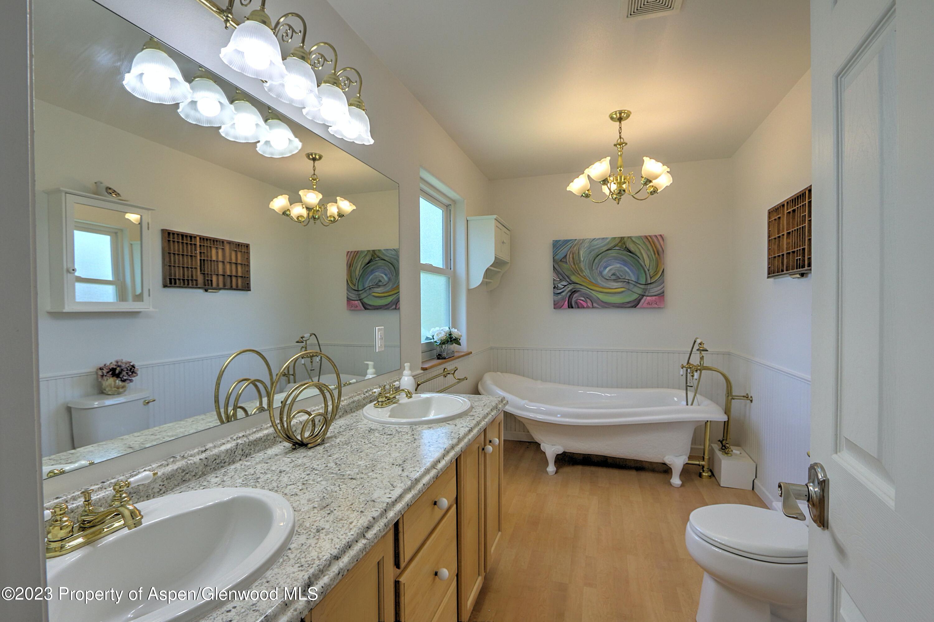 1527 Graham Court Rifle, CO 81650 - Photo 20 of 32 a bathroom with a granite countertop bathtub a sink and a mirror