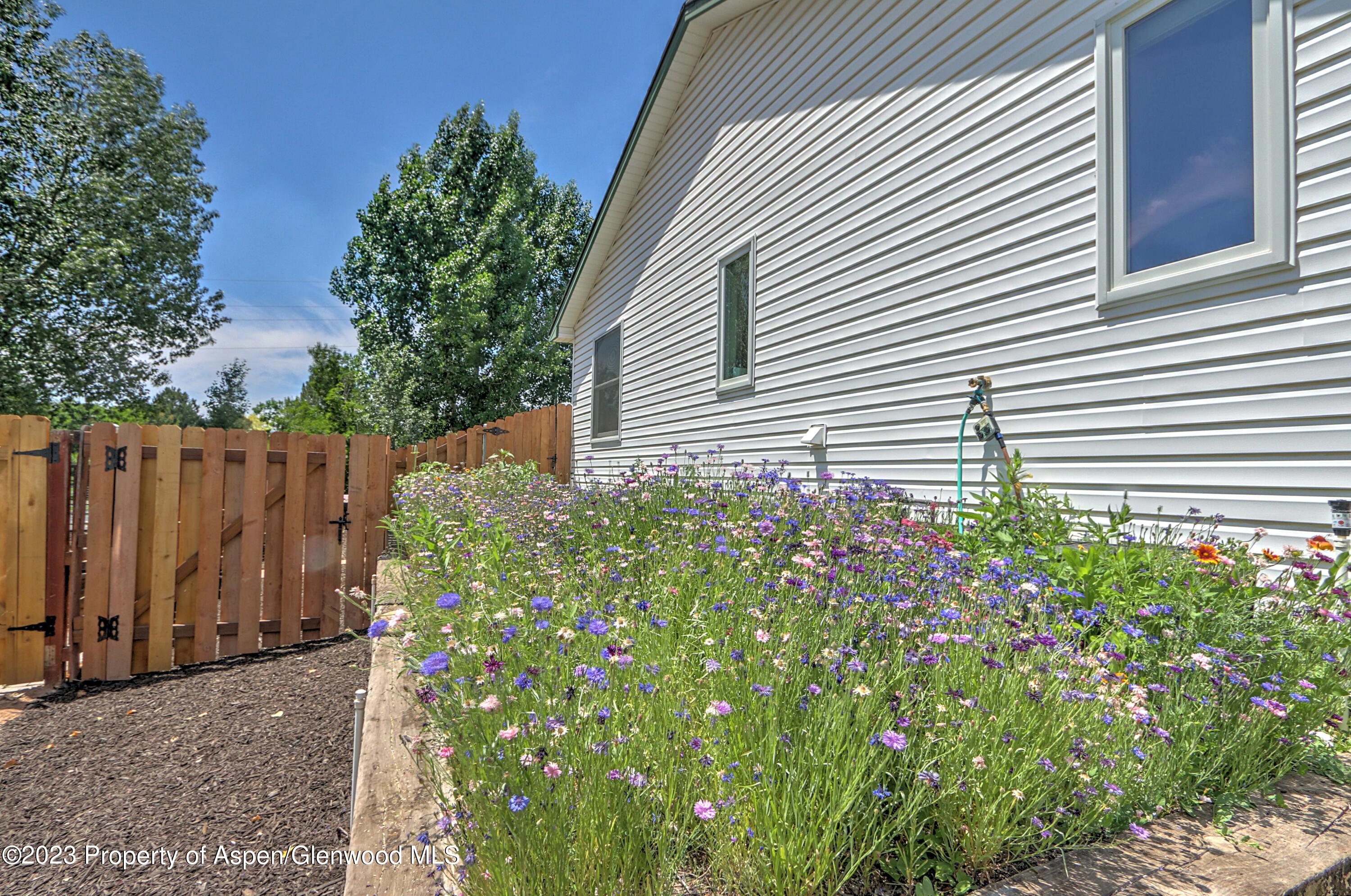 1527 Graham Court Rifle, CO 81650 - Photo 5 of 32 a small white house with a flower garden in front of it