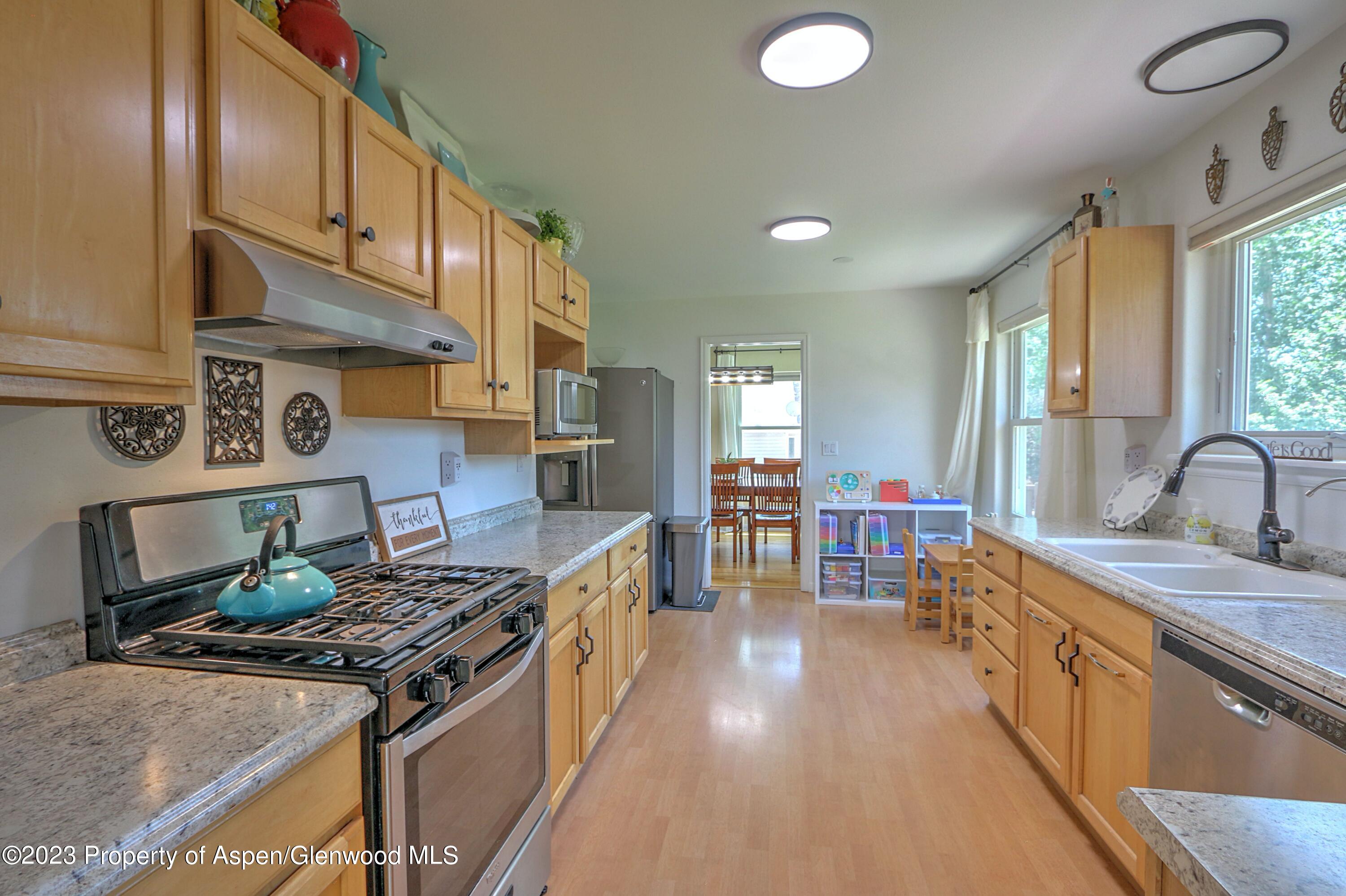 1527 Graham Court Rifle, CO 81650 - Photo 10 of 32 a kitchen with stainless steel appliances granite countertop a stove a sink dishwasher and cabinets with wooden floor