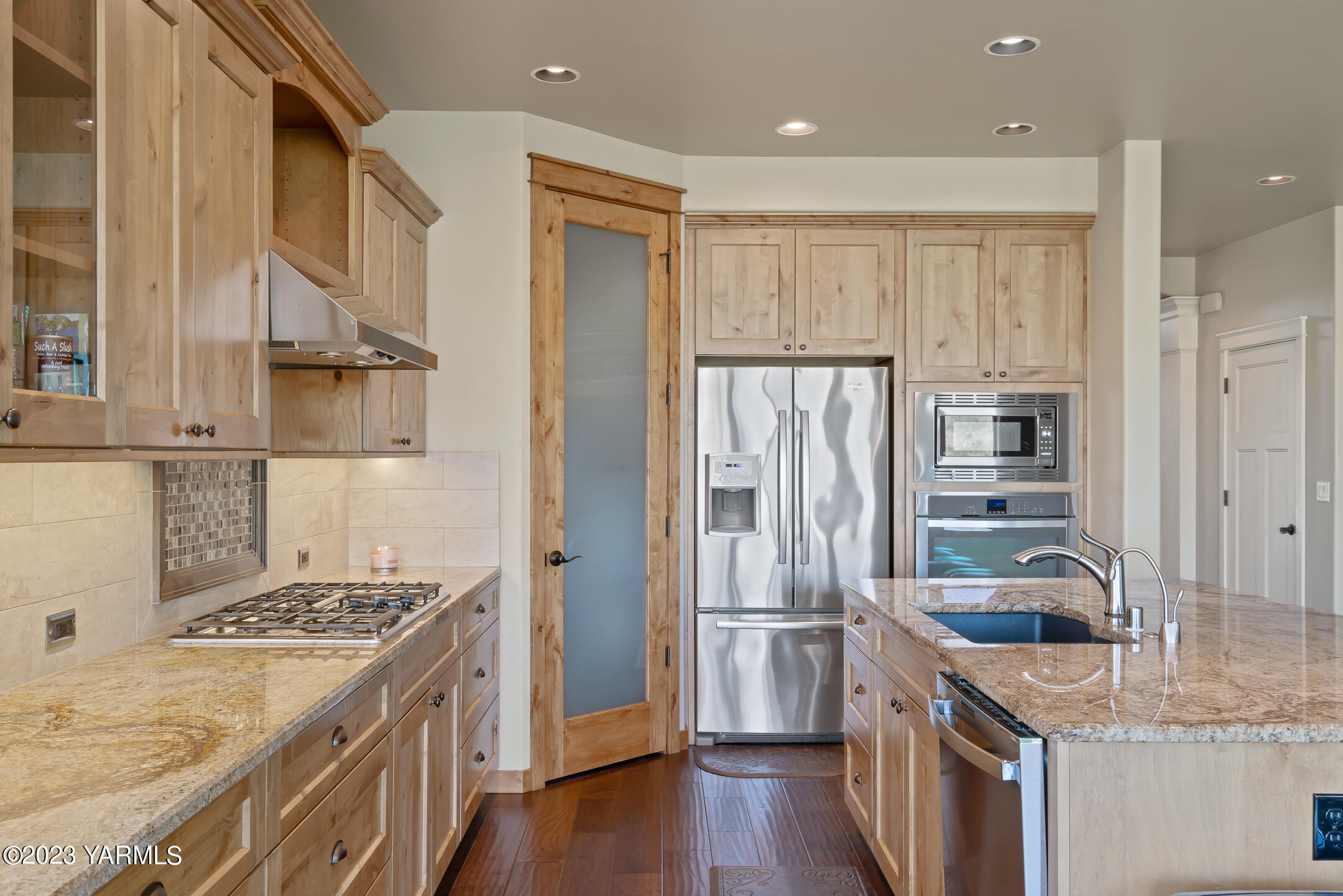 2978 Crosswater Loop Richland, WA 99354 - Photo 12 of 34 a kitchen with stainless steel appliances granite countertop a refrigerator a stove and a sink with wooden floors