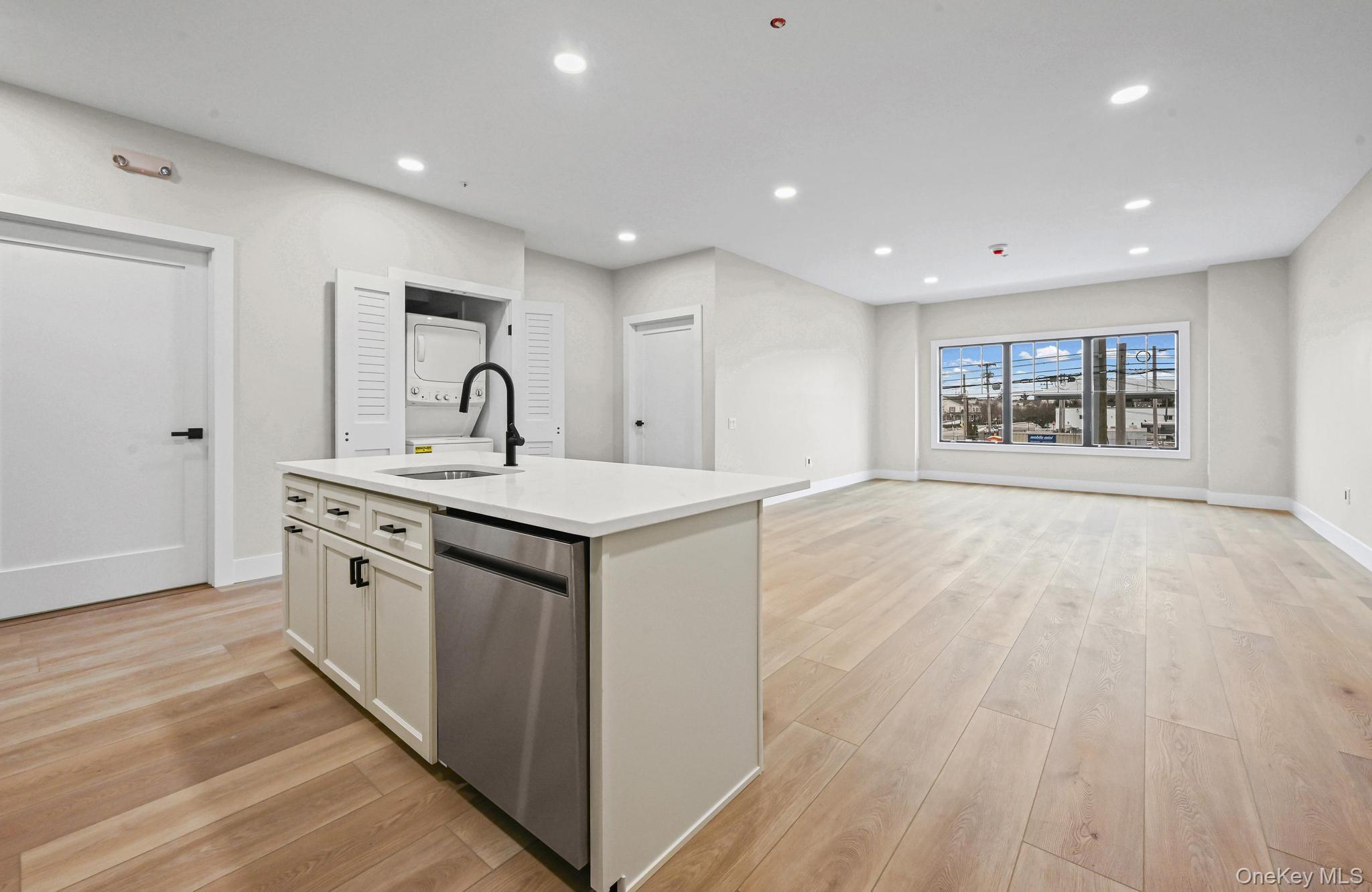 80 Division Street, Unit 2G Patchogue, NY 11772 - Photo 3 of 9 a large white kitchen with stainless steel appliances granite countertop a large counter top a sink and a refrigerator