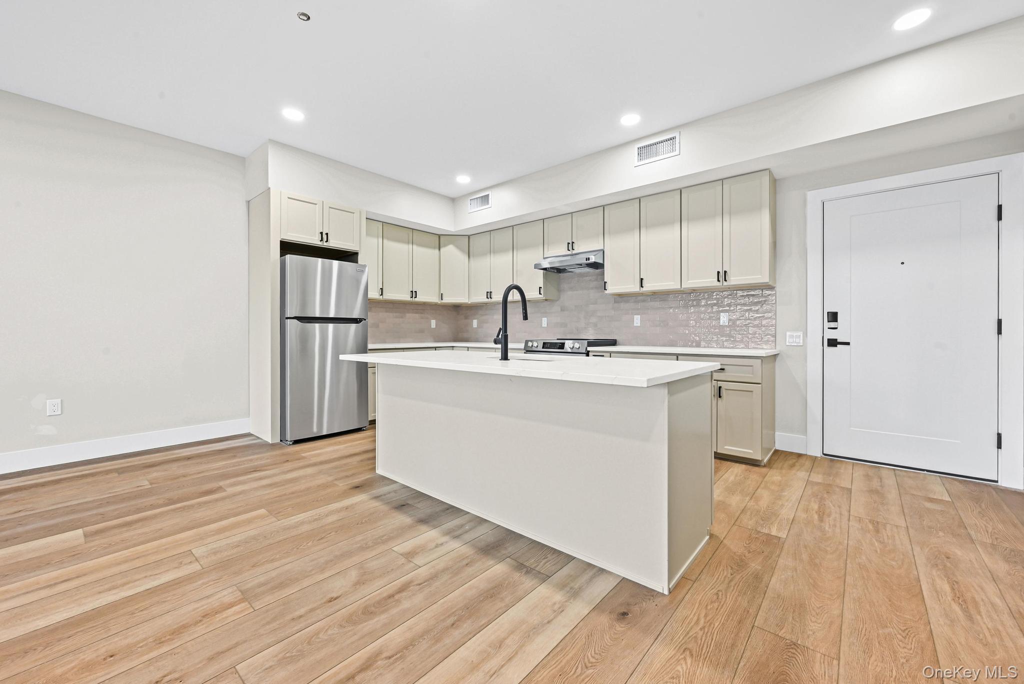 80 Division Street, Unit 2G Patchogue, NY 11772 - Photo 4 of 9 a kitchen with a sink a window stainless steel appliances and cabinets