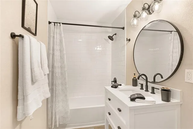 a bathroom with a sink vanity mirror and tub