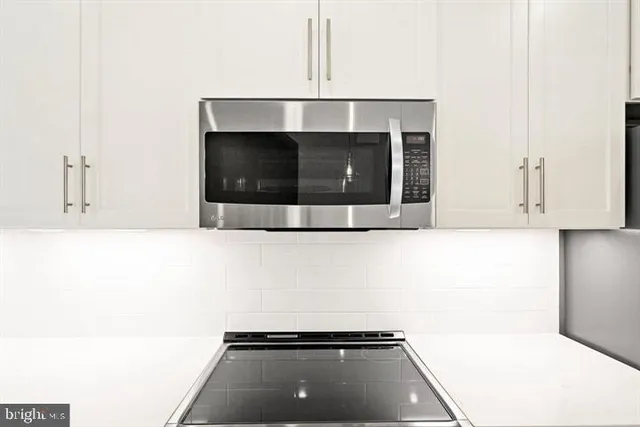 a view of an empty room with wooden floor and kitchen