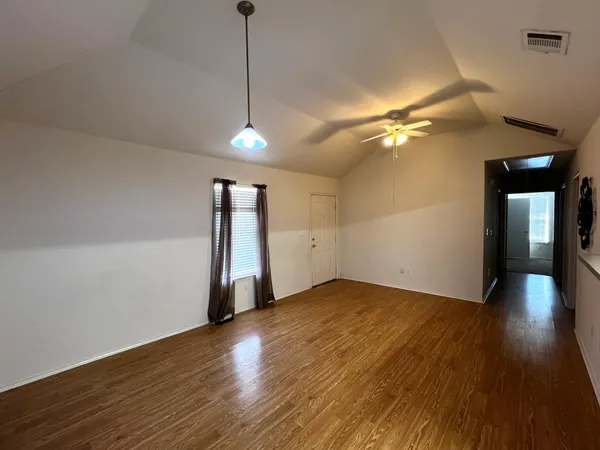 a view of an empty room with window and wooden floor