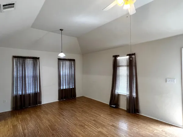 an empty room with wooden floor and windows
