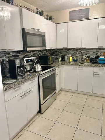 a kitchen with stainless steel appliances white cabinets and a stove top oven