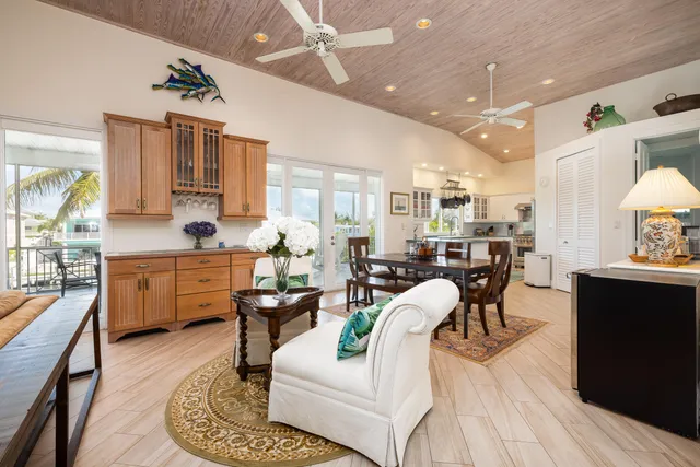 a view of a dining room and livingroom with furniture wooden floor a rug a fireplace and a chandelier