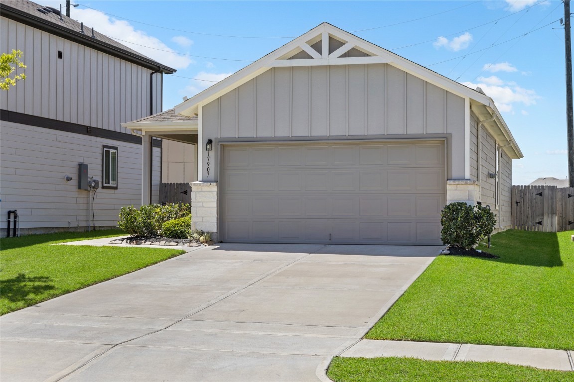 17907 Grain Auger Road Hockley, TX 77447 - Photo 1 of 24 charming single-story home with a two-car garage. The exterior features light-color siding and a neatly manicured lawn, providing a welcoming and well-maintained appearance. The driveway is spacious, and there's a small garden area near the entrance.