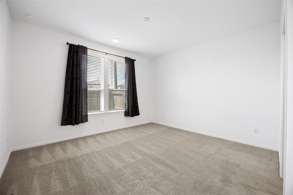 17907 Grain Auger Road Hockley, TX 77447 - Photo 19 of 24 clean, neutral-color walls and carpet, with a large window that provides ample natural light, complemented by dark curtains. It's a bright and versatile space suitable for a bedroom or office.