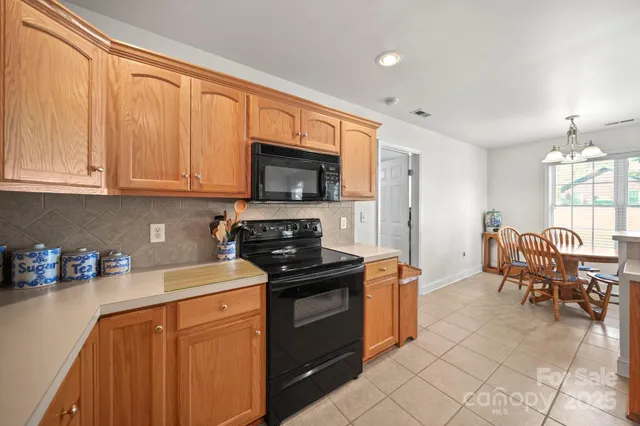 a kitchen with stainless steel appliances granite countertop a stove top oven a sink dishwasher and a refrigerator with wooden cabinets