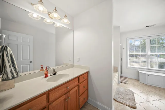 a bathroom with a sink vanity granite tub and a mirror