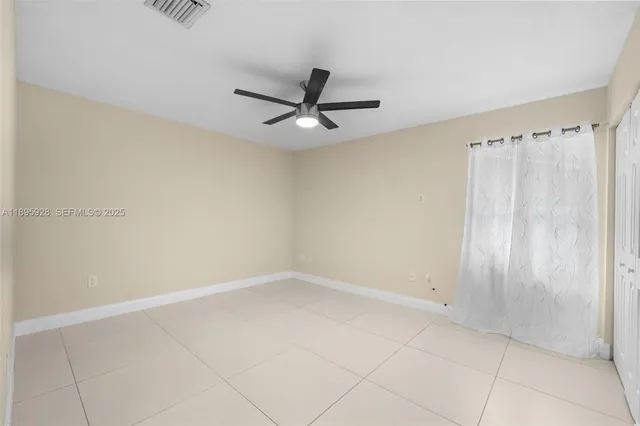 an empty room with a ceiling fan and carpet