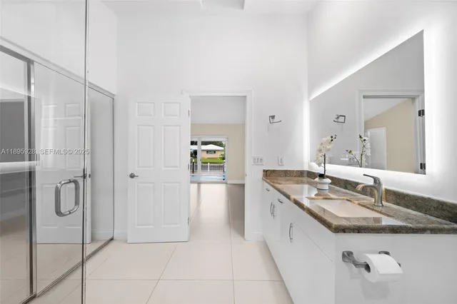 a spacious bathroom with a granite countertop sink a mirror and shower