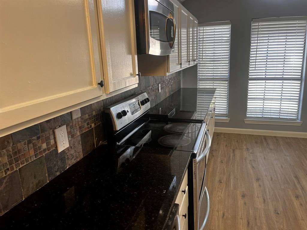 1007 Mack Place Denton, TX 76209 - Photo 10 of 37 Kitchen with stainless steel appliances, tasteful backsplash, wood finished floors, and dark stone countertops