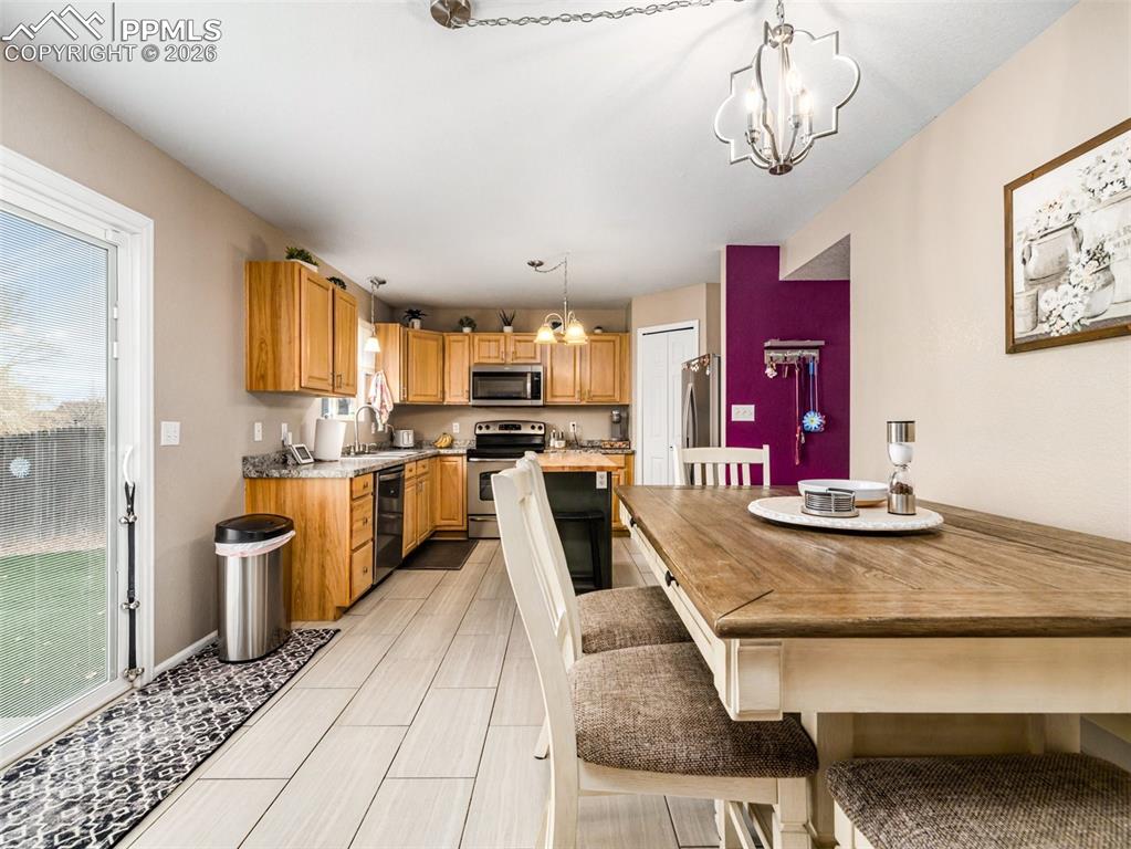 5044 Landmark Road Pueblo, CO 81008 - Photo 7 of 25 a kitchen with stainless steel appliances kitchen island granite countertop a stove a refrigerator a sink dishwasher with a dining table and chairs