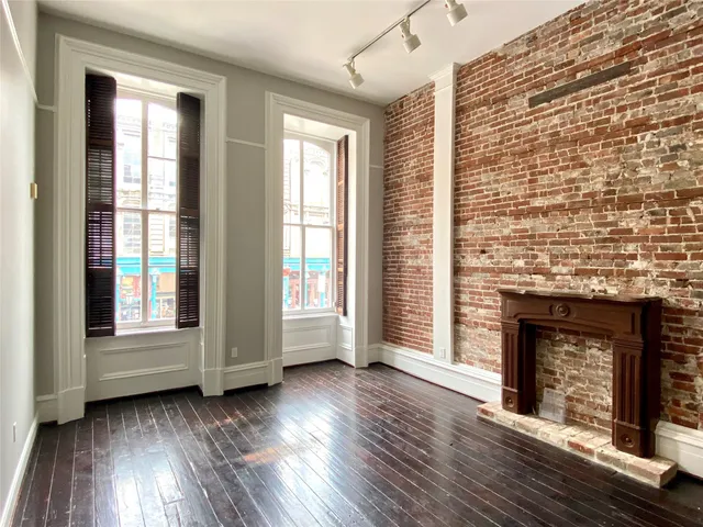 an empty room with wooden floor fireplace and windows