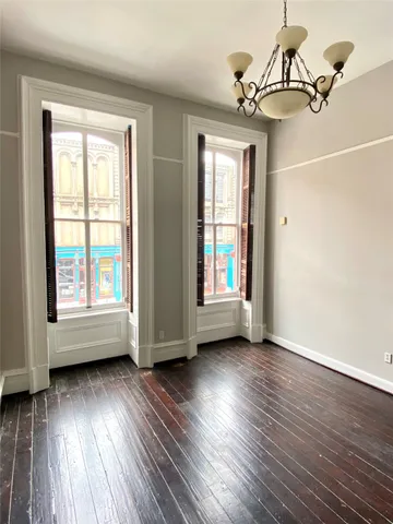 a view of an empty room with wooden floor and chandelier