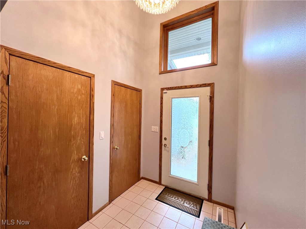 Tiled foyer entrance with an inviting chandelier and a high ceiling