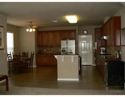 a kitchen with kitchen island granite countertop a refrigerator a stove a sink dishwasher a dining table and chairs with wooden floor