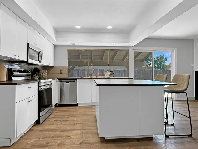 a kitchen with kitchen island granite countertop wooden floors and white stainless steel appliances