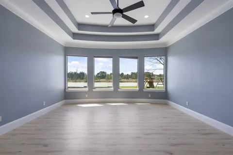 a view of an empty room with chandelier fan and windows
