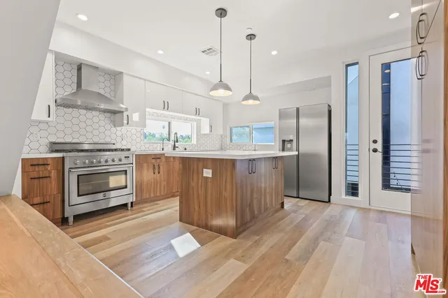a kitchen with stainless steel appliances granite countertop a stove a refrigerator and a wooden floors