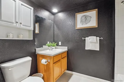 a bathroom with a granite countertop sink a toilet and mirror