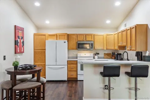 a kitchen with stainless steel appliances granite countertop a refrigerator a stove a sink dishwasher and white cabinets with wooden floor