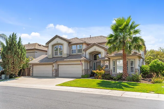 a front view of a house with a garden and trees