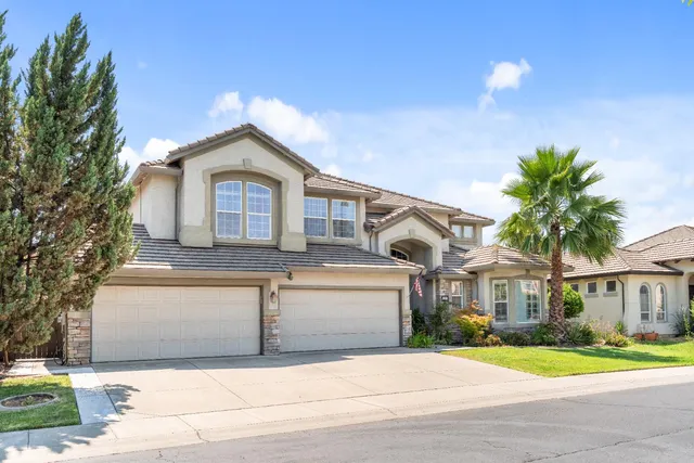 a front view of a house with a garden and trees
