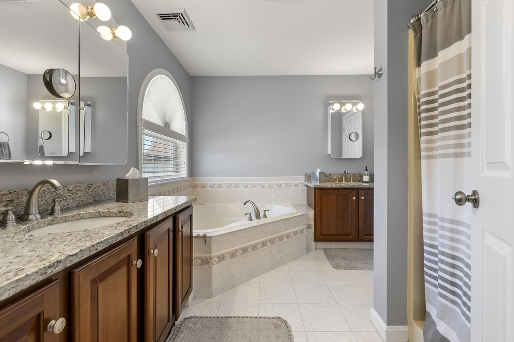 16 Windsor Street Everett, MA 02149 - Photo 17 of 40 a bathroom with a granite countertop sink a large mirror and a bathtub with shower