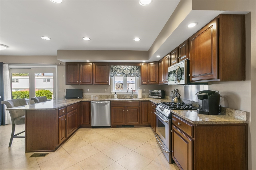 16 Windsor Street Everett, MA 02149 - Photo 8 of 40 a kitchen with stainless steel appliances granite countertop wooden cabinets a stove top oven and a dishwasher