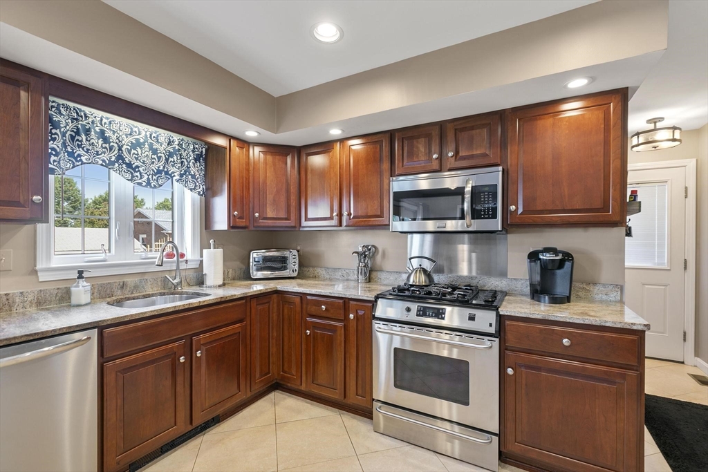 16 Windsor Street Everett, MA 02149 - Photo 9 of 40 a kitchen with stainless steel appliances wooden cabinets and a stove top oven
