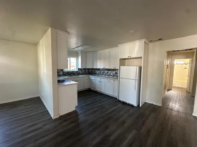 a kitchen with granite countertop a refrigerator and a stove top oven