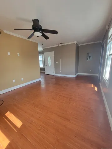 an empty room with wooden floor ceiling fan and windows