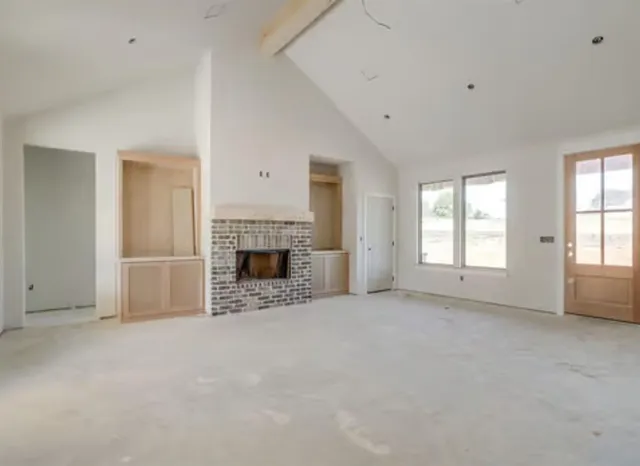 an empty room with windows and fireplace