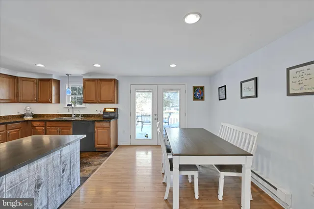 a kitchen with granite countertop a stove top oven a sink dishwasher a dining table and chairs with wooden floor