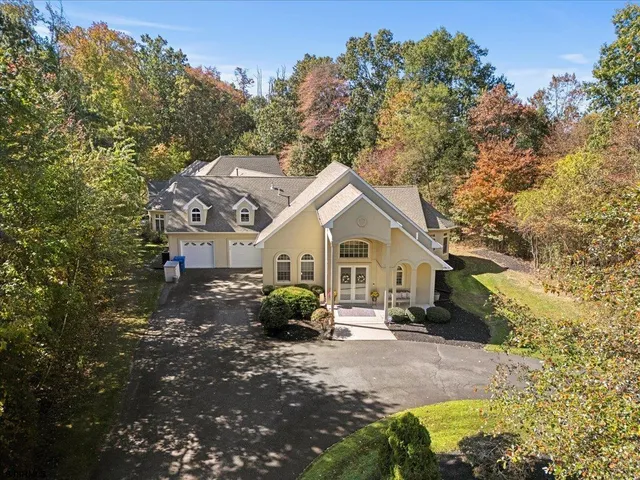 a view of a white house next to a yard with large trees